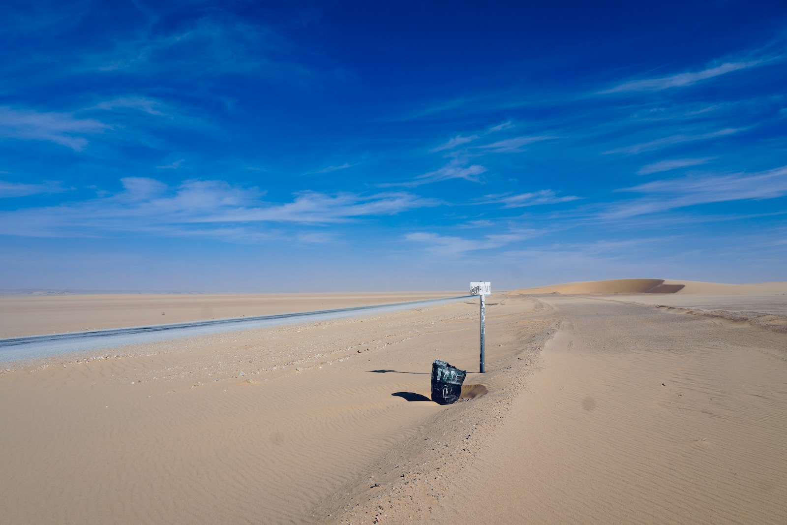 a street sign on a sandy beach under a blue sky